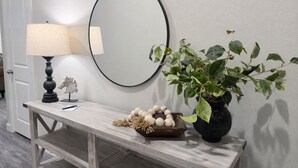 Una consola de madera con una lámpara, un espejo, una planta en maceta y objetos decorativos.