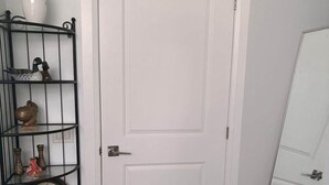 A white door with a small shelf above it holding a clock, a vase with a plant, and a decorative item. - One bedroom and one washroom (Oakville)