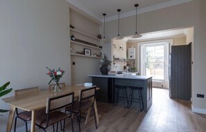 Eine moderne Küche mit Essbereich, Holzboden und Pendelleuchten.