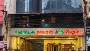 A hotel with a reflective glass facade and a neon sign in multiple languages. - Hotel Raya's Annexe 1 (Kumbakonam)