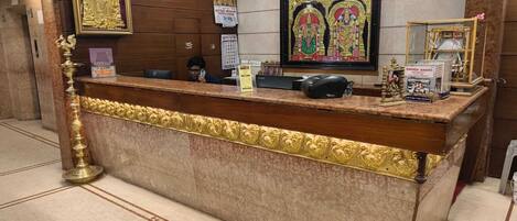 Un mostrador de recepción con encimera de mármol, obras de arte enmarcadas encima y una lámpara decorativa a un lado.