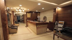 A reception area with a counter, seating, and a chandelier. - Hotel Raya's Annexe 1 (Kumbakonam)