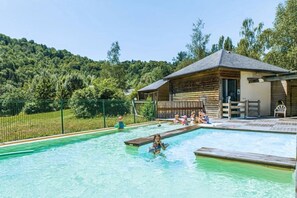 Une piscine avec une terrasse en bois et un bâtiment en arrière-plan.