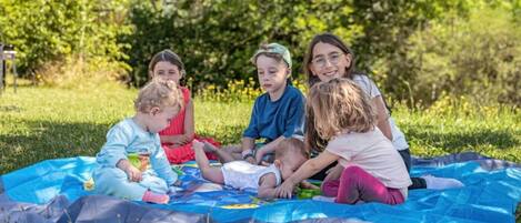 A group of children sitting on a blue blanket outdoors.