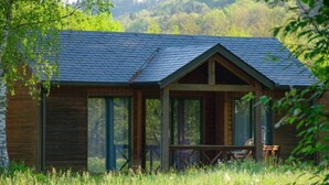 Una cabaña de madera con techo inclinado, ventanas amplias y un porche.