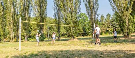 Una red de voleibol en un parque con árboles y césped.