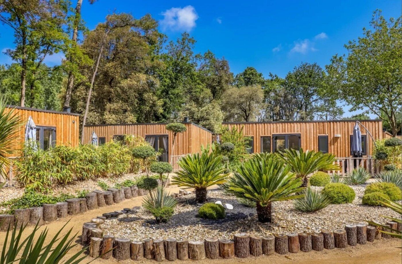 A modern wooden cabin with a garden area featuring various plants and a wooden deck.