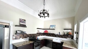 A modern kitchen with dark cabinetry, a central island, a built-in oven, and a stainless steel refrigerator.