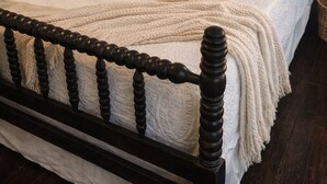 A neatly made bed with a dark wooden headboard, white bedding, and a bedside table with a lamp, books, and a vase of flowers. - Closest Stay to Corry House and Durhamtown Off Road Resort!! Historic House (Union Point)