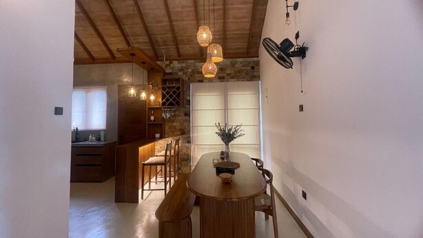 A dining area with a wooden table and chairs, a vase with flowers, and pendant lights. - Alo Kai Villa (Weligama)