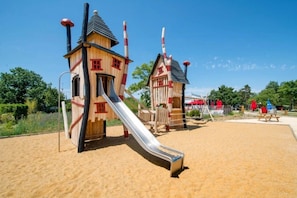 Ein Spielplatz mit zwei hölzernen Spielhäusern und einer Rutsche.