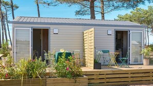 A small, single-story cabin with a sliding door and a patio area. - ZEcamping 3* toboggans mobil-home TV 16m2 2 pers (Quinéville)