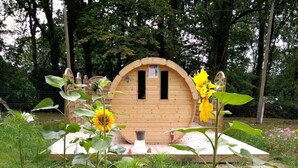 Een houten constructie met een ronde ingang, omgeven door een tuin met verschillende planten en bloemen.