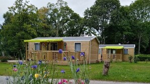 Een houten hutje met een veranda, omgeven door een tuin vol verschillende bloemen.