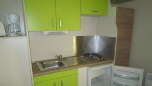 A compact kitchen with green cabinets, a sink, a stove, and a dishwasher.