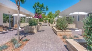 A courtyard with a paved walkway, planters with shrubs, and outdoor seating. - Hotel Sabhè (Gallipoli)