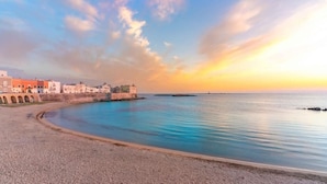 A coastal town with a beach, a sea wall, and buildings along the shore. - Hotel Sabhè (Gallipoli)