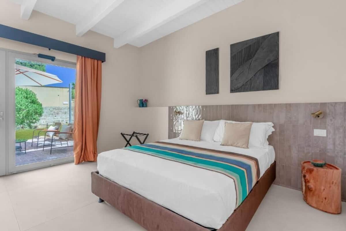 Un dormitorio con una cama grande, un ventanal corredero a un patio y dos obras de arte abstracto en la pared.