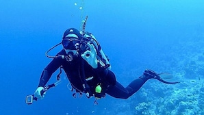 A diver underwater with a camera and a light.