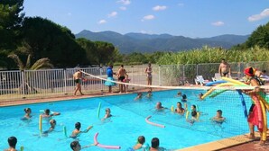A swimming pool with people in the water, surrounded by a fence and trees. - ZEcamping 3* piscine chauffée animations locatif 20m2 5 pers (Saint-Jean-Pla-de-Corts)