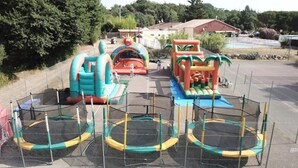 An outdoor playground with inflatable slides and trampolines. - ZEcamping 3* piscine chauffée animations locatif 20m2 5 pers (Saint-Jean-Pla-de-Corts)