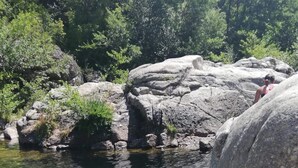 Una piscina naturale rocciosa circondata da massi imponenti e fitta vegetazione.