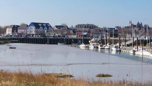 Ein Yachthafen mit vertäuten Booten, eine Uferpromenade und Wohnhäuser im Hintergrund.