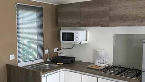 Eine kompakte Küche mit integriertem Mikrowellenherd, Gasherd und Kaffeemaschine.