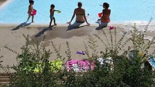 Un espace piscine comprenant plusieurs bassins, entouré de verdure et surplombé par un ciel dégagé.