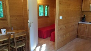 L’intérieur d’un chalet en bois comprend un coin repas, un banc rouge et un espace cuisine.