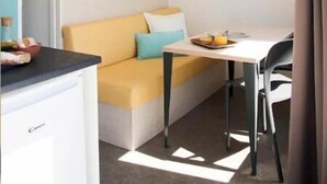 Una camera d'albergo compatta con angolo cottura, una piccola zona pranzo e un divano.