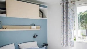 Una camera da letto con un letto, un comodino, uno scaffale sopra il letto e una finestra con tende.