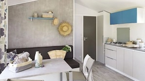 Une cuisine moderne avec des meubles blancs, un coin repas comprenant une table et des chaises, et un mur d’accent gris agrémenté d’objets décoratifs.