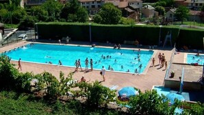 Une grande piscine extérieure entourée de maisons et de verdure.