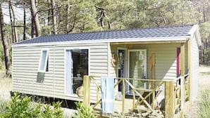 Une petite maison mobile d’un seul étage, dotée d’une véranda, d’une porte coulissante et d’une fenêtre.