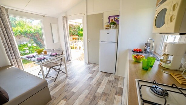 Une cuisine compacte comprenant un coin repas, un réfrigérateur, une cuisinière et une machine à café.