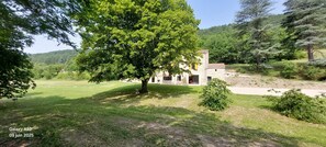 Il s’agit d’une propriété comprenant un bâtiment en pierre, un grand arbre et une zone herbeuse.