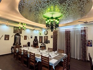 Zona pranzo con tavolo rotondo, sedie, un lampadario e soffitto decorato.