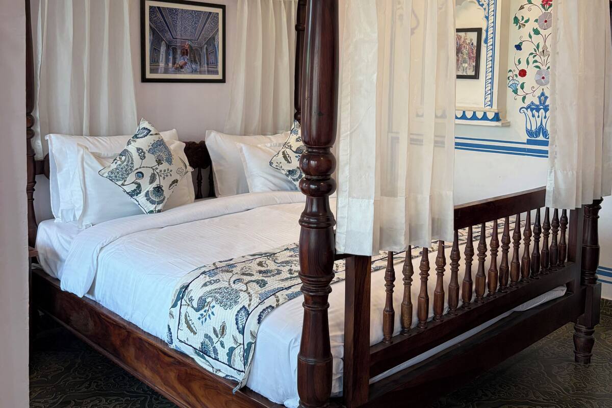 Una cama con dosel, ropa de cama blanca y almohadas decorativas.