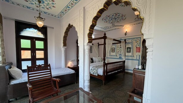 A room with a bed, a sofa, a glass table, and a decorative ceiling. - Jharokha Heritage Hotel Jaipur (Jaipur)