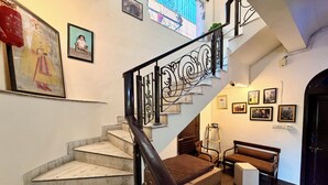 A staircase with a black railing, a sofa, and framed pictures on the walls. - Jharokha Heritage Hotel Jaipur (Jaipur)