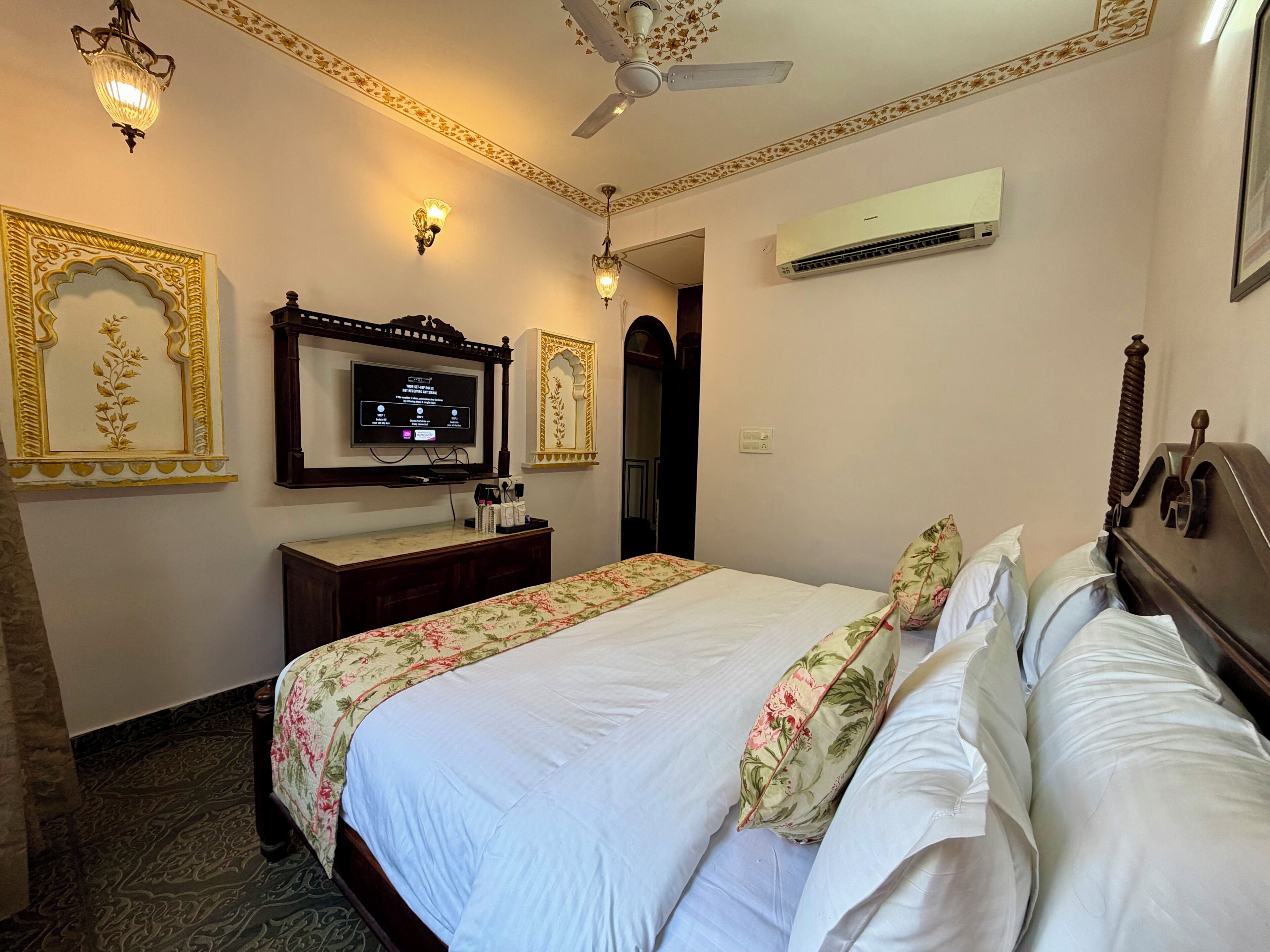 Une chambre d’hôtel équipée d’un lit, d’une télévision, d’un bureau et d’un miroir.