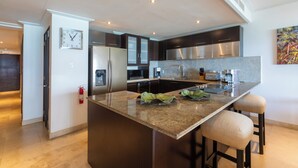 Une cuisine moderne dotée d’un îlot central, d’appareils électroménagers en acier inoxydable et d’une horloge murale.