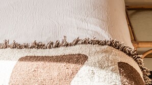 A bed with a white pillow and a patterned blanket.