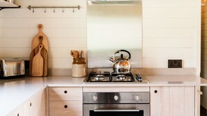 A kitchen with a stainless steel range hood, a gas stove, a toaster, and wooden utensils on the counter.