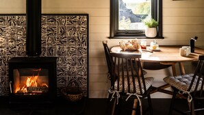A cozy room with a fireplace, a dining table, chairs, and a window with a view.