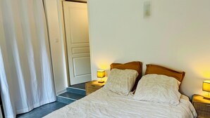 Een slaapkamer met een bed, twee nachtkastjes met lampen, een deur en een gordijn.