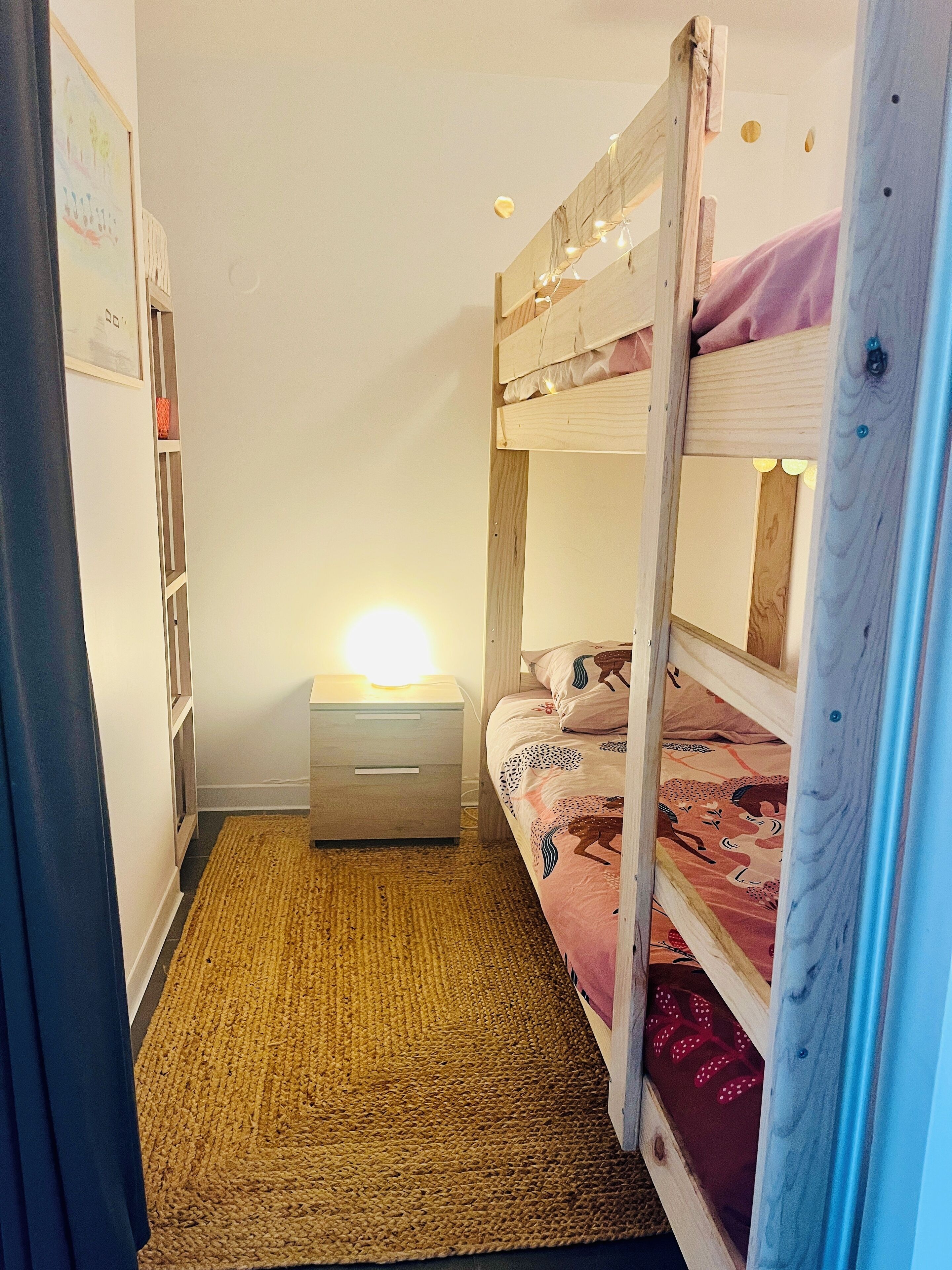 A bunk bed room with a bedside table and a lamp.