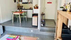 Een ruimtelijke woonkamer met eethoek, keuken en een kleine inkom.