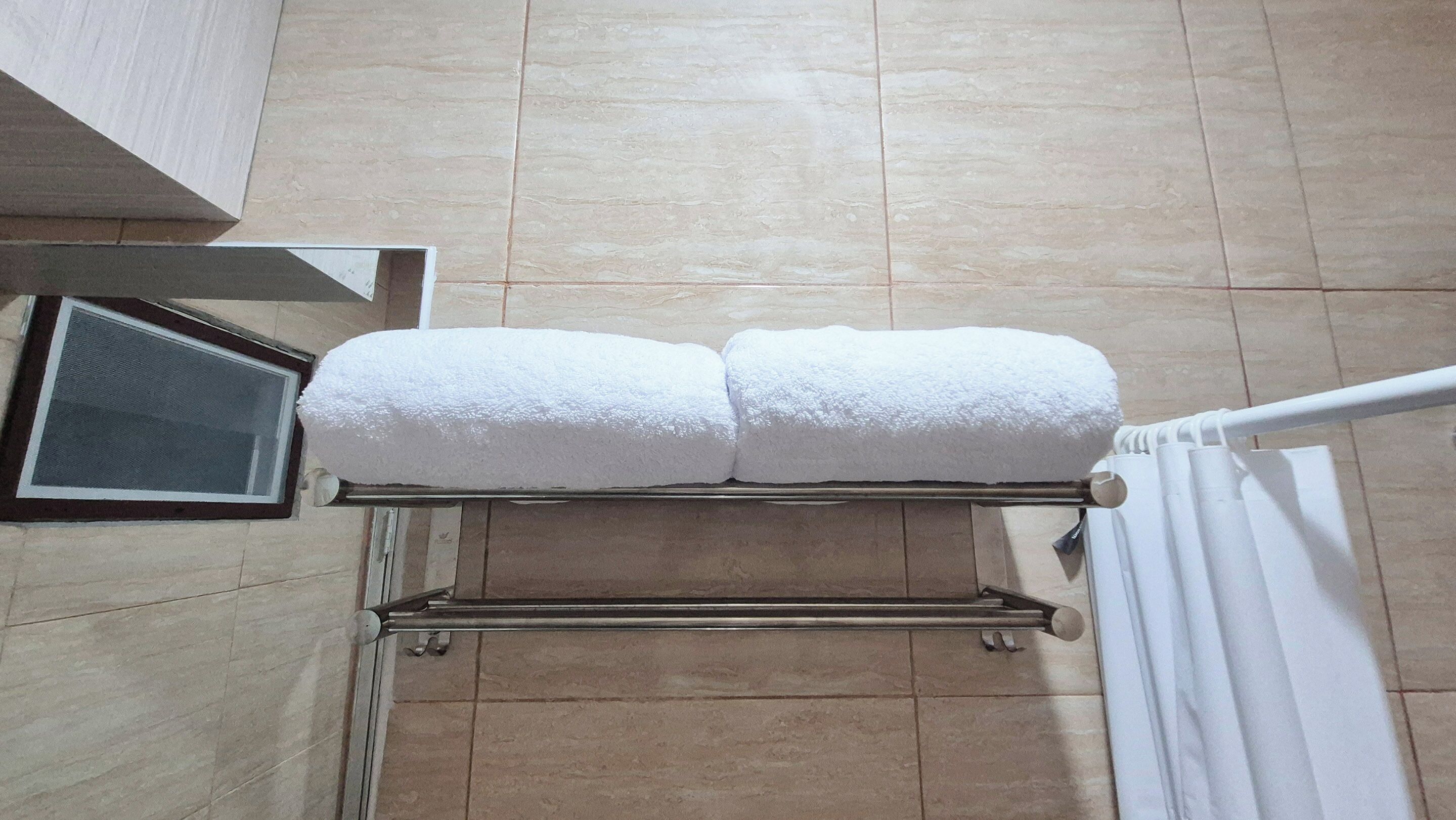 A bathroom with a towel rack holding two white towels.